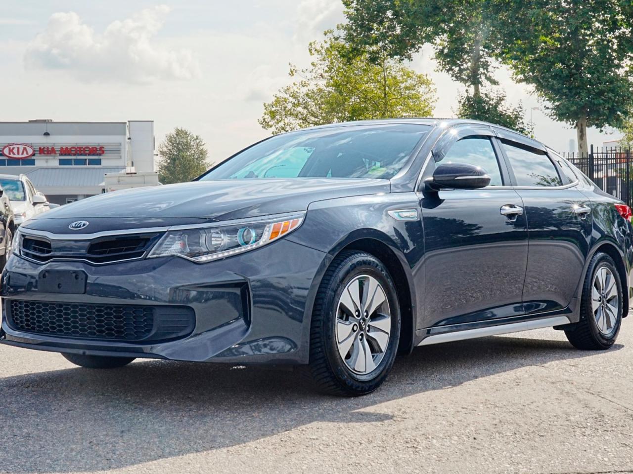 Experience Efficiency and Style with the Pre-Owned 2017 Kia Optima Hybrid LX!When it comes to finding the perfect blend of efficiency, comfort, and style, the 2017 Kia Optima Hybrid LX is your answer. This sleek and reliable sedan offers exceptional fuel economy without compromising on performance or features. Heres why the Optima Hybrid LX is the ideal choice for you:Efficient Hybrid Powertrain: The gas/electric hybrid system in this Optima ensures youll enjoy excellent fuel efficiency, while still enjoying a smooth and responsive drive. Say goodbye to frequent trips to the gas station and hello to more time on the road.Modern Exterior Design: The stunning grey exterior color gives the Optima Hybrid LX a sophisticated and timeless look, while the bold design cues command attention on the road. Youll turn heads wherever you go.Comfortable and Spacious Interior: Step inside and be greeted by the spacious and luxurious black cloth seats that provide comfort on long drives. The multi-zone climate control system ensures you and your passengers stay comfortable in any weather condition.Convenience and Connectivity: With keyless entry, power windows, and power door locks, youll enjoy effortless access to your vehicle. The Bluetooth connection allows you to stay connected and hands-free while on the move, and the hands-free liftgate makes loading and unloading a breeze.Safety Features: Rest easy knowing that the Optima Hybrid LX is equipped with a range of safety features to protect you and your loved ones. The rear-view camera and rear head airbags provide increased visibility and protection when maneuvering, while stability control and brake assist offer added peace of mind.Top-Notch Technology: The Optima Hybrid LX features an MP3-capable AM/FM stereo system, satellite radio, and steering wheel audio controls, providing you with a premium entertainment experience on every drive. The integrated turn signal mirrors and automatic headlights offer enhanced visibility and safety.Drive with Confidence: With stability control and tire pressure monitoring, youll have peace of mind on every journey. The advanced telematics system keeps you connected and informed about your vehicles performance.Dont miss your chance to own the efficient and stylish 2017 Kia Optima Hybrid LX. Contact us today to schedule a test drive and experience the perfect combination of efficiency and style for yourself!