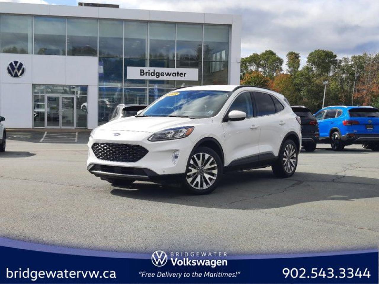 White 2021 Ford Escape Titanium Hybrid Apple CarPlay | Android Auto | Sirus XM AWD eCVT 2.5L iVCT Bridgewater Volkswagen, Located in Bridgewater Nova Scotia.2.5L iVCT, eCVT, AWD, 10 Speakers, 2.91 Axle Ratio, 4-Wheel Disc Brakes, ABS brakes, Air Conditioning, Alloy wheels, AM/FM radio: SiriusXM, Auto High-beam Headlights, Auto-dimming Rear-View mirror, Automatic temperature control, Block heater, Brake assist, Bumpers: body-colour, Compass, Delay-off headlights, Driver door bin, Driver vanity mirror, Dual front impact airbags, Dual front side impact airbags, Electronic Fuel Door Release, Electronic Stability Control, Emergency communication system: SYNC 3 911 Assist, Four wheel independent suspension, Front anti-roll bar, Front Bucket Seats, Front dual zone A/C, Front fog lights, Front reading lights, Fully automatic headlights, Garage door transmitter, HD Radio, Heated ActiveX Material Sport Contour Bucket Seats, Heated door mirrors, Heated front seats, Heated steering wheel, Illuminated entry, Knee airbag, Lane Departure Warning System, Low tire pressure warning, Memory seat, Navigation System, Neutral Towing Capability, Occupant sensing airbag, Outside temperature display, Overhead airbag, Overhead console, Panic alarm, Passenger door bin, Passenger vanity mirror, Pedestrian Alert Sounder, Power door mirrors, Power driver seat, Power Liftgate, Power passenger seat, Power steering, Power windows, Radio data system, Radio: B&O Sound System by Bang & Olufsen w/SiriusXM, Rain sensing wipers, Rear anti-roll bar, Rear reading lights, Rear window defroster, Rear window wiper, Remote keyless entry, Roof rack: rails only, Security system, Speed control, Speed-sensing steering, Speed-Sensitive Wipers, Split folding rear seat, Spoiler, Steering wheel mounted audio controls, SYNC 3 Communications & Entertainment System, SYNC 3/Apple CarPlay/Android Auto, Telescoping steering wheel, Tilt steering wheel, Traction control, Trip computer, Variably intermittent wipers, Wheels: 19 Machined-Face Aluminum.Certification Program Details: 150 Points Inspection Fresh Oil Change Free Carfax Full Detail 2 years MVI Full Tank of Gas The 150+ point inspection includes: Engine Instrumentation Interior components Pre-test drive inspections The test drive Service bay inspection Appearance Final inspection