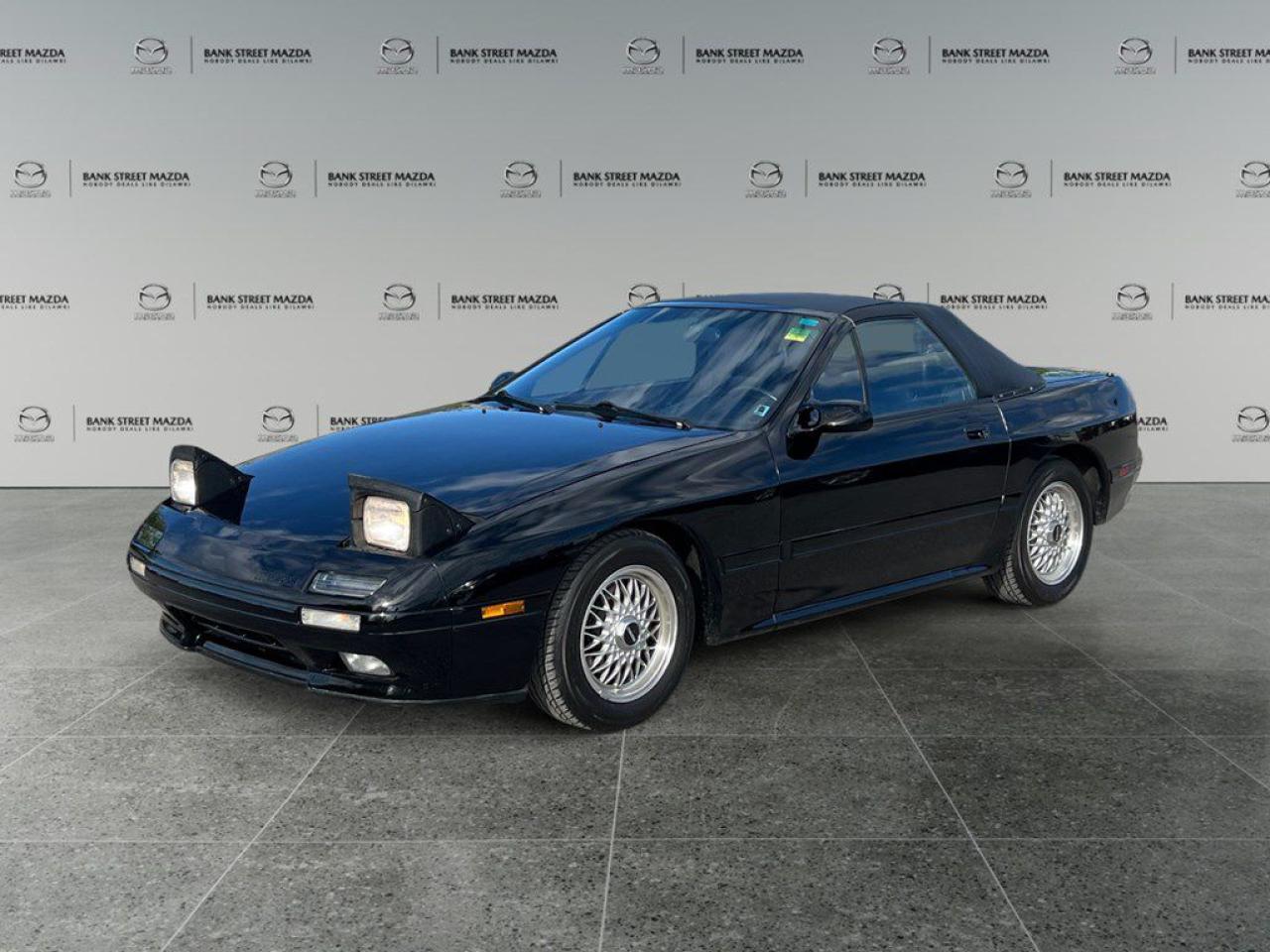 The Mazda Rx-7 RX-7 in its classic 1990 iteration is a remarkable vehicle that combines a timeless color palette with rear-wheel drive perfection. Its design promotes agile handling, providing an exhilarating driving experience on any road. The exterior boasts the iconic styling of the early 90s with its aerodynamic silhouette and compact form, capturing the essence of that eras sports car aesthetics. Inside, the driver-oriented cockpit focuses on functionality, with meticulously crafted controls that are both intuitive and accessible. Equipped with essential technology for its time, this Rx-7 might include a basic audio system and certain rudimentary safety features. While it doesnt have modern driver assistance systems, its core engineering was designed to offer a pure and engaging drive. This classic coupe beckons to true automotive enthusiasts and collectors who appreciate the heritage and driving purity of the Mazda Rx-7 RX-7. Reach out to the dealership to learn more about this iconic vehicle and make a piece of automotive history your own.