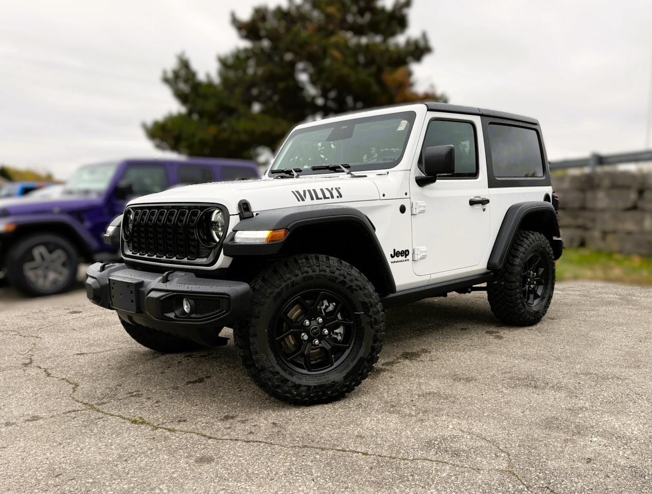 Our New 2026 Jeep Wrangler Willys 2 Door 4X4 with the Convenience Pack in Bright White rides with renowned capability that true adventurers love! Driven by a TurboCharged 2.0 Litre 4 Cylinder supplying 270hp to an 8 Speed Automatic transmission with an Off-Road Plus mode for enhanced trail performance. Dana axles and an electronic locking rear differential help you conquer almost any conditions, and this Four Wheel Drive SUV returns approximately 10.2L/100km on the highway. Eye-catching Willys hood graphics help our Wrangler grab attention with LED lighting, fog lamps, alloy wheels, fender flares, a sport bar, and a fantastic open-air driving experience when you drop the Black 3-piece Freedom top, fold down the Gorilla Glass windshield, and remove the doors!  Thanks to our Convenience Pack, you can feel good with the top up or down in our Willys cabin. It bundles heated cloth seats, a heated-wrapped steering wheel, automatic climate control, remote start, and a 7-inch driver display for better driving. Uconnect&reg; technology powers your infotainment system to enjoy a 12.3-inch touchscreen, 3.5-inch driver display, Apple CarPlay&reg;, WiFi compatibility, Android Auto&reg;, Bluetooth&reg;, and an eight-speaker audio system.  Stay safe as you dominate your days, knowing Jeep has your back with automatic braking, adaptive cruise control, a rearview camera, forward collision warning, trailer sway damping, hill start assistance, and more. The world awaits, and our Wrangler Willys is ready to go! Save this Page and Call for Availability. We Know You Will Enjoy Your Test Drive Towards Ownership!