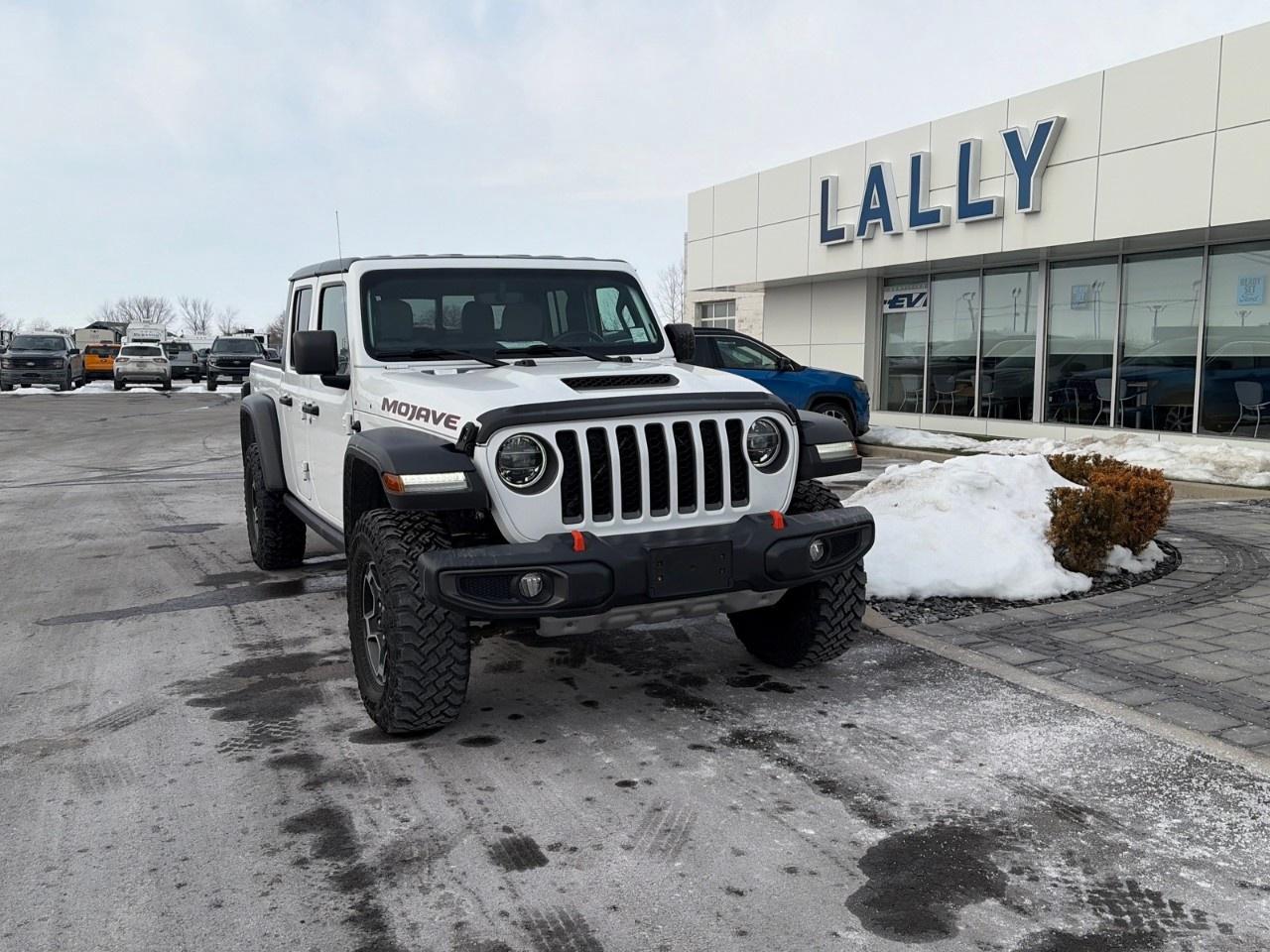 <p>The <strong>2021 Jeep Gladiator Mojave 4×4</strong> with the <strong>3.6 L Pentastar VVT V6</strong> and <strong>6-speed manual transmission</strong> is a desert-tuned, midsize 4WD pickup built for high-speed off-road performance and everyday use. Its naturally aspirated 3.6 L V6 makes about <strong>285 hp and 260 lb-ft of torque</strong>, paired to a six-speed manual and part-time four-wheel-drive system with a manual transfer case for driver control. The Mojave trim adds reinforced suspension with <strong>FOX internal-bypass shocks, heavy-duty components and a 4.10 axle ratio</strong> to improve handling on loose sand and rough terrain, along with skid plates and rugged off-road features. It maintains the Gladiators utility with a five-seat cabin and pickup bed while prioritizing capability and driver engagement in challenging environments.</p>