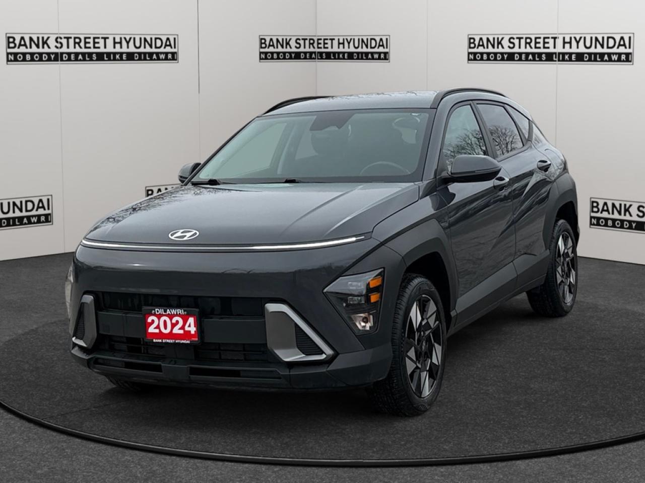 The 2024 Hyundai Kona 2.0L Preferred AWD is now available in an elegant Gray finish, combining advanced handling with the convenience of AWD, making it perfect for those looking for confidence in various driving conditions. This SUVs exterior is accentuated by stylish alloy wheels that complement its modern design. The interior offers a range of comforts including leather steering wheel, heated steering wheel, and heated front seats, ensuring a pleasurable experience regardless of the season. Keyless entry and power windows add to the overall ease and accessibility. The Kona comes equipped with a host of technological features to enhance your driving experience. From the backup camera to brake assist, every ride is safer and more enjoyable. Stay connected with smart device integration and enjoy the entertainment options on satellite radio. Advanced features such as lane assist and adaptive cruise control provide an extra layer of safety and convenience, whether on a long highway cruise or a daily city drive. Perfect for tech-savvy families and urban adventurers, this 2024 Hyundai Kona is equipped to meet your lifestyle needs. Contact us today to learn more about how you can own this feature-rich SUV.