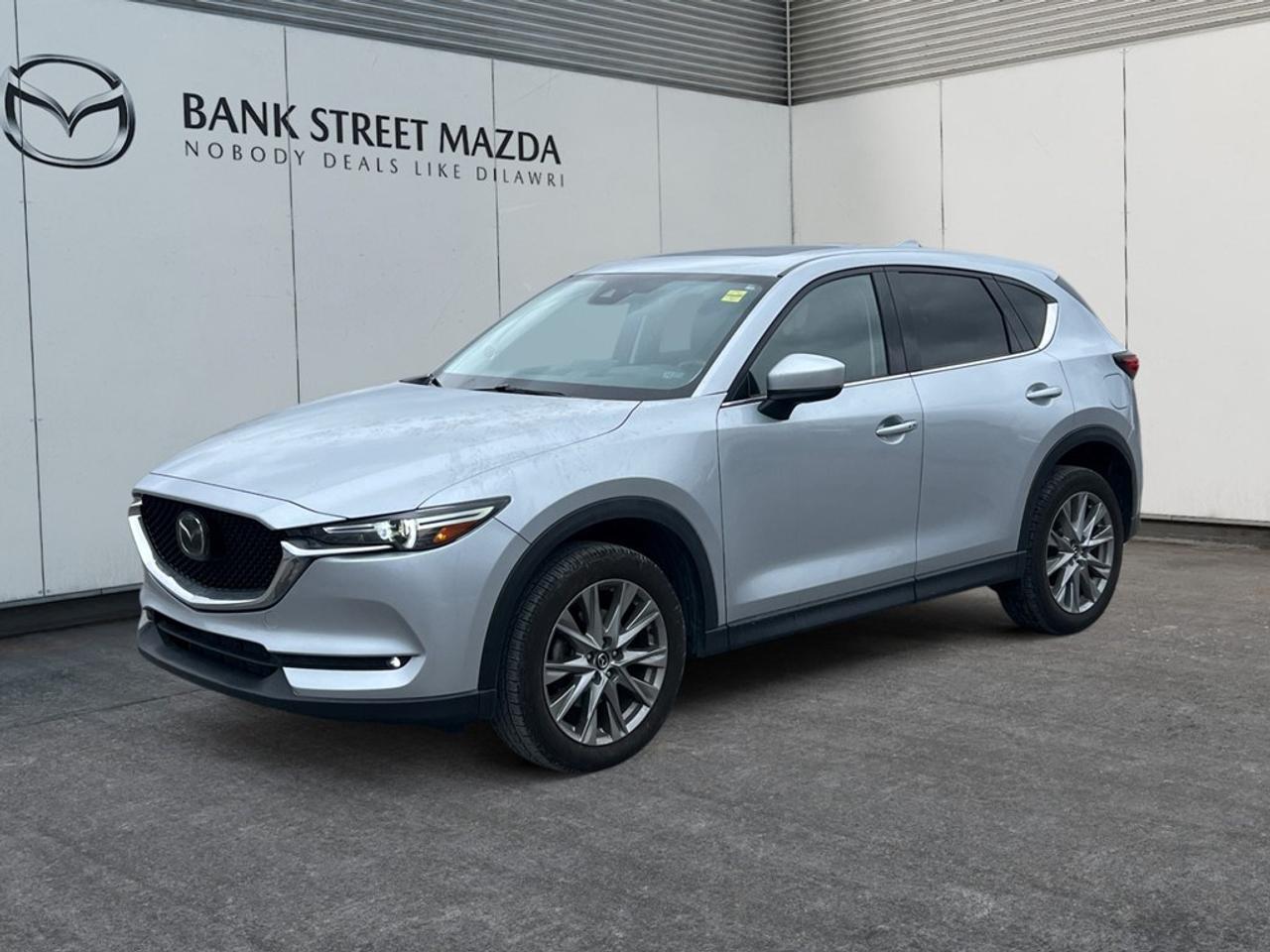 The 2021 Mazda CX-5 GT w/Turbo in an elegant Silver hue redefines driving dynamics with its AWD system, offering excellent handling and stability. This SUV is perfect for those who appreciate both style and substance. On the outside, the CX-5 exudes confidence and charm, while its refined interior boasts sophisticated leather seating, an elegant leather steering wheel, and leatherette door trim. Alloy wheels and a sunroof add to its top-tier appearance and provide a perfect touch of luxury and comfort. Technologically advanced, this model includes a cutting-edge heads-up display and a comprehensive navigation system. Stay connected with Bluetooth and the smart device integration, while the satellite radio keeps your entertainment options varied. Enjoy the ease of keyless entry, and drive with peace of mind thanks to modern safety features like lane assist, adaptive cruise control, and a backup camera. Ideal for families or individuals who prioritize comfort and safety without sacrificing performance, this Mazda CX-5 promises an experience beyond mere transportation. Contact our dealership today to learn more about how this stylish and tech-savvy SUV can be yours.