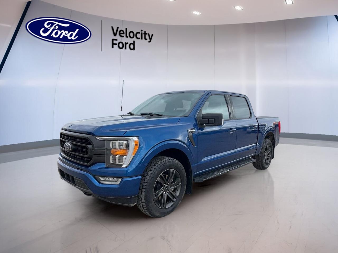 Built to handle work, weather, and daily driving with ease, this 2022 Ford F-150 XLT 4WD 5.5 Box delivers proven capability in a smart, well-equipped package. Finished in blue with a black interior, this used truck offers four doors, automatic transmission, a 2.7-litre unleaded engine, and 133,570 km.

At Velocity Ford in Moose Jaw, this 2022 Ford F-150 XLT 4WD 5.5 Box stands out for its balanced mix of strength, comfort, and practical technology. Four-wheel drive adds confidence on rough roads and winter streets, while useful features like navigation, blind spot monitoring, and a backup camera help make every trip easier.

FEATURES OF THE F-150 XLT 4WD 5.5 Box
»» 2.7-litre EcoBoost gas engine performance
»» Automatic transmission with dual shift mode
»» Four-wheel drive for added traction
»» 5.5-foot box for daily utility

TRUCK FEATURES
»» Tows up to 4,580 kg confidently
»» Rear tow hook supports truck utility
»» Off-road tires add extra grip
»» Four-door cab improves passenger access

ADVANCED SAFETY FEATURES
»» Backup camera helps with reversing
»» Blind spot monitor boosts lane awareness
»» Lane departure warning adds confidence
»» Side and head airbags protection

PERFORMANCE AND EFFICIENCY
»» 2.7-litre unleaded engine feels responsive
»» Automatic transmission shifts smoothly daily
»» Four-wheel drive supports changing conditions
»» Cruise control helps on longer drives

COMFORT AND CONVENIENCE
»» Front air conditioning keeps cabin comfortable
»» Power windows add everyday convenience
»» Heated mirrors help in cold weather
»» Driver and passenger lumbar support

TECHNONOLGY AND CONNECTIVITY
»» Navigation system helps guide each trip
»» Bluetooth integration supports hands-free calling
»» WiFi hotspot keeps devices connected
»» Satellite radio expands entertainment choices

CARGO SPACE
»» 5.5-foot box handles useful loads
»» Rear trunk access aids cargo reach
»» Spare tire supports peace of mind
»» Four doors simplify loading personal gear

AWARDS & RECOGNITIONS
»» North American Truck of the Year, North American Car, Truck and Utility Vehicle of the Year, 2021

WHAT OTHER OWNERS LIKE
»» Strong towing for work and recreation
»» Comfortable ride for everyday use
»» User-friendly cabin technology and controls
»» Confident four-wheel drive capability year-round

This 2022 Ford F-150 XLT 4WD 5.5 Box is equipped with many of the features drivers want most in a full-size pickup. Cruise control, power steering, anti-lock braking system, stability control, child safety locks, automatic headlights, fog lights, tire pressure monitoring, tinted windows, and automatic door locks all add real everyday value.

This 2022 Ford F-150 XLT 4WD 5.5 Box also includes electric mirrors, heated mirrors, steering wheel audio controls, an adjustable steering wheel, rear window defroster, passenger airbag sensor, illuminated vanity mirrors, and rear tow hook capability. It is a practical truck with the equipment needed for commuting, hauling, and weekend duties alike.

This 2022 Ford F-150 XLT 4WD 5.5 Boxs VIN is: 1FTEW1EP7NKE21189.