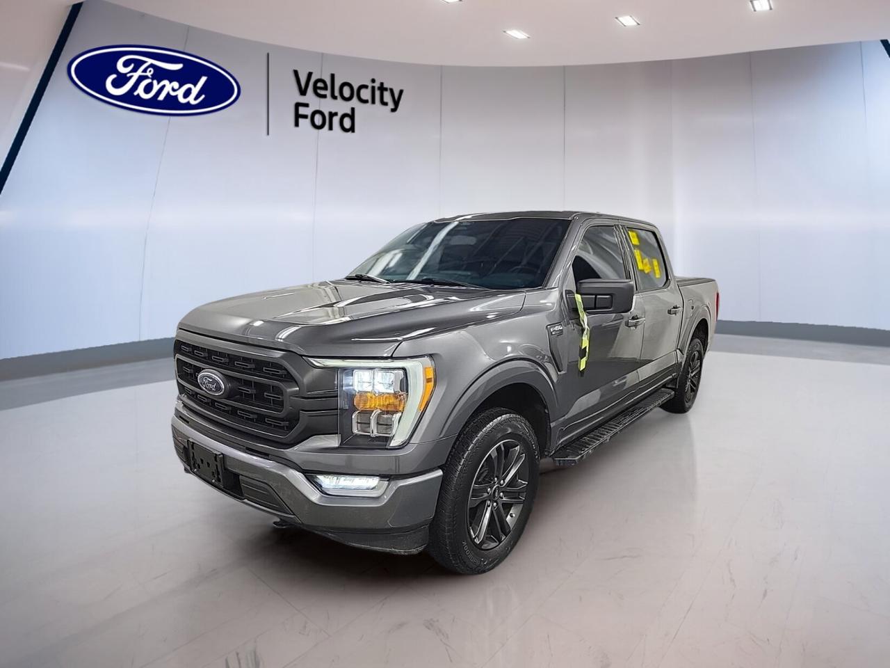 Built for hard work and daily comfort, this used 2022 Ford F-150 XLT 4WD SuperCrew 5.5 Box is a smart full-size truck for drivers in Moose Jaw. It pairs a capable 2.7-litre unleaded engine with an automatic transmission and four-wheel drive for confident performance in changing Prairie conditions.

Finished in Grey with a Black interior, this 2022 Ford F-150 XLT 4WD SuperCrew 5.5 Box offers a roomy four-door cabin and practical features that matter every day. With 65,162 km on the odometer, it delivers strong utility, modern safety, and the flexibility truck buyers expect from a proven Ford pickup.

FEATURES OF THE F-150 XLT 4WD SuperCrew 5.5 Box COMING SOON

»» Grey exterior with Black interior
»» Four-door SuperCrew cab adds rear space
»» Automatic transmission with dual shift mode
»» 2.7-litre unleaded engine with four-wheel drive

TRUCK FEATURES

»» Towing capacity rated at 4,580 kg
»» Rear tow hook supports truck utility
»» Off-road tires add extra traction
»» 5.5-foot box supports daily hauling

ADVANCED SAFETY FEATURES

»» Backup camera helps with reversing confidence
»» Blind spot monitor adds traffic awareness
»» Lane departure warning supports safer travel
»» Side and head airbags enhance protection

PERFORMANCE AND EFFICIENCY

»» 2.7-litre unleaded engine balances power efficiently
»» Automatic transmission delivers smooth daily driving
»» Four-wheel drive adds year-round traction
»» Stability control supports secure road handling

COMFORT AND CONVENIENCE

»» Cruise control helps on longer drives
»» Front air conditioning keeps cabin comfortable
»» Power windows add everyday convenience
»» Heated mirrors help in cold weather

TECHNONOLGY AND CONNECTIVITY

»» Navigation system helps guide each trip
»» Bluetooth integration supports hands-free communication
»» WiFi hotspot keeps devices connected
»» Satellite radio expands entertainment choices

CARGO SPACE

»» Rear trunk access improves loading convenience
»» SuperCrew cabin adds flexible storage room
»» Spare tire supports travel readiness
»» Four doors ease passenger and cargo access

AWARDS & RECOGNITIONS

»» North American Truck of the Year, North American Car, Truck and Utility Vehicle of the Year, 2021
»» Best Buy Award, The Car Guide, 2022

WHAT OTHER OWNERS LIKE

»» Smooth ride quality for daily use
»» Strong towing ability for weekend tasks
»» Spacious crew cab for family comfort
»» User-friendly tech and practical controls

This Ford F-150 stands out with useful equipment chosen for real-world driving. Included features such as Anti-Lock Braking System, tire pressure monitoring, automatic headlights, fog lights, child safety locks, passenger airbag sensor, and automatic door locks add peace of mind and convenience on every trip.

Inside, this truck is set up to make long days easier. Power steering, an adjustable steering wheel, steering wheel audio controls, driver and passenger lumbar support, illuminated vanity mirrors, rear window defroster, tinted windows, and electric mirrors all help create a comfortable and functional cabin environment.

For drivers who need a dependable pickup with everyday usability, this 2022 Ford F-150 XLT 4WD SuperCrew 5.5 Box is a well-rounded choice at Velocity Ford in Moose Jaw. It combines trusted Ford capability, modern driver-assist features, and strong towing strength in one practical package.

This 2022 Ford F-150 XLT 4WD SuperCrew 5.5 Box COMING SOONs VIN is: 1FTEW1EP4NKF08659.