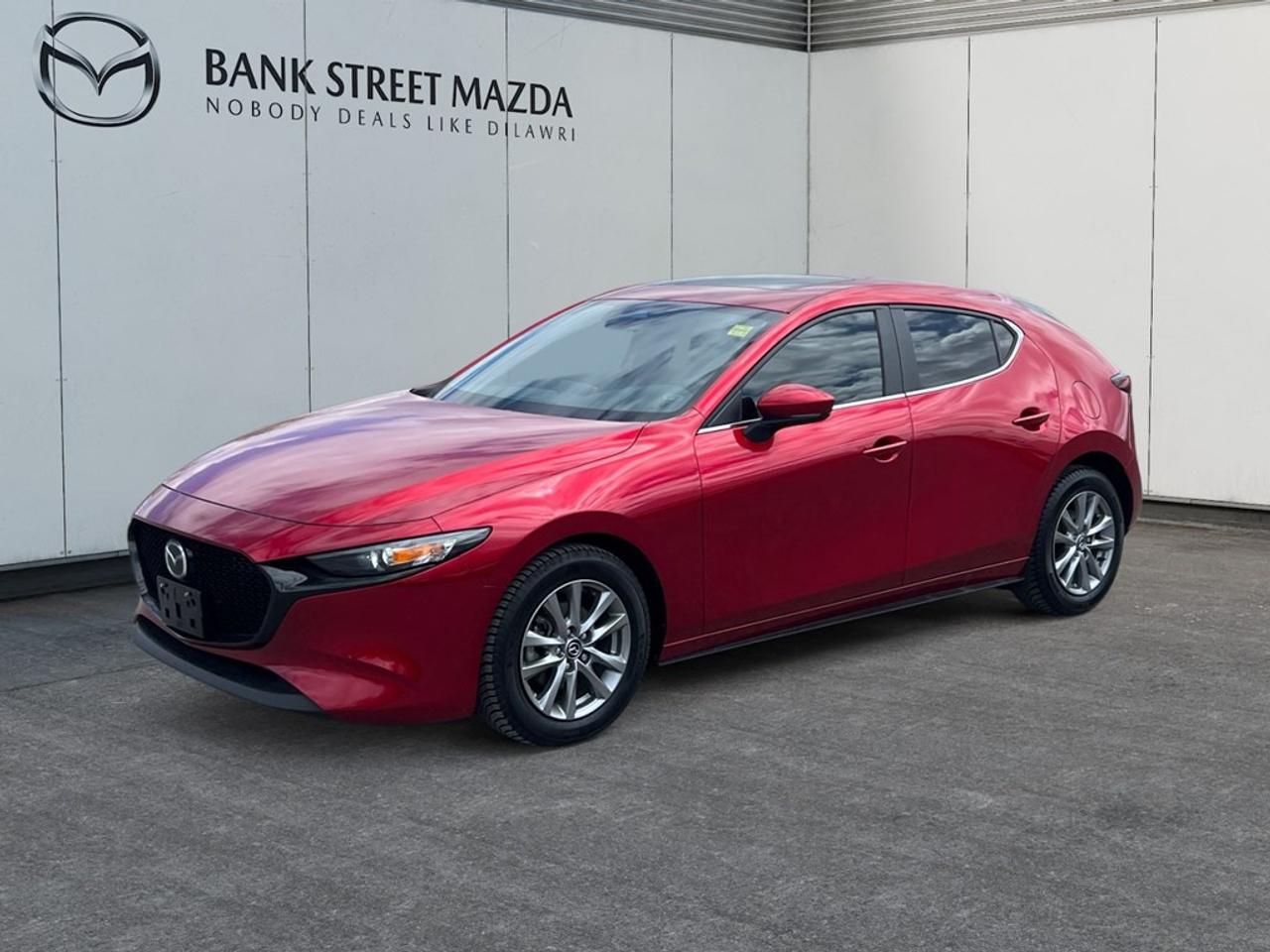 The 2024 Mazda Mazda3 Sport GS in radiant Red boasts a dynamic presence and a front-wheel-drive (FWD) system paired with precise handling. This sedan promises a driving experience where style meets function. The striking red exterior is accentuated by sleek alloy wheels, providing a sophisticated edge. Inside, the cabin is designed with comfort in mind, featuring heated front seats, a leather steering wheel, and a leather gear shifter, all adding a touch of luxury to your daily drive. Stay connected and secure with cutting-edge technology like smart device integration and Bluetooth connectivity for seamless communication. Safety features such as a backup camera, lane assist, and adaptive cruise control enhance your confidence on the road. Perfect for those who value a blend of performance and style, the Mazda3 Sport GS is ideal for individuals seeking a versatile and reliable vehicle. Contact the dealership today to learn more and schedule a test drive to experience the perfect amalgamation of technology, comfort, and driving pleasure.