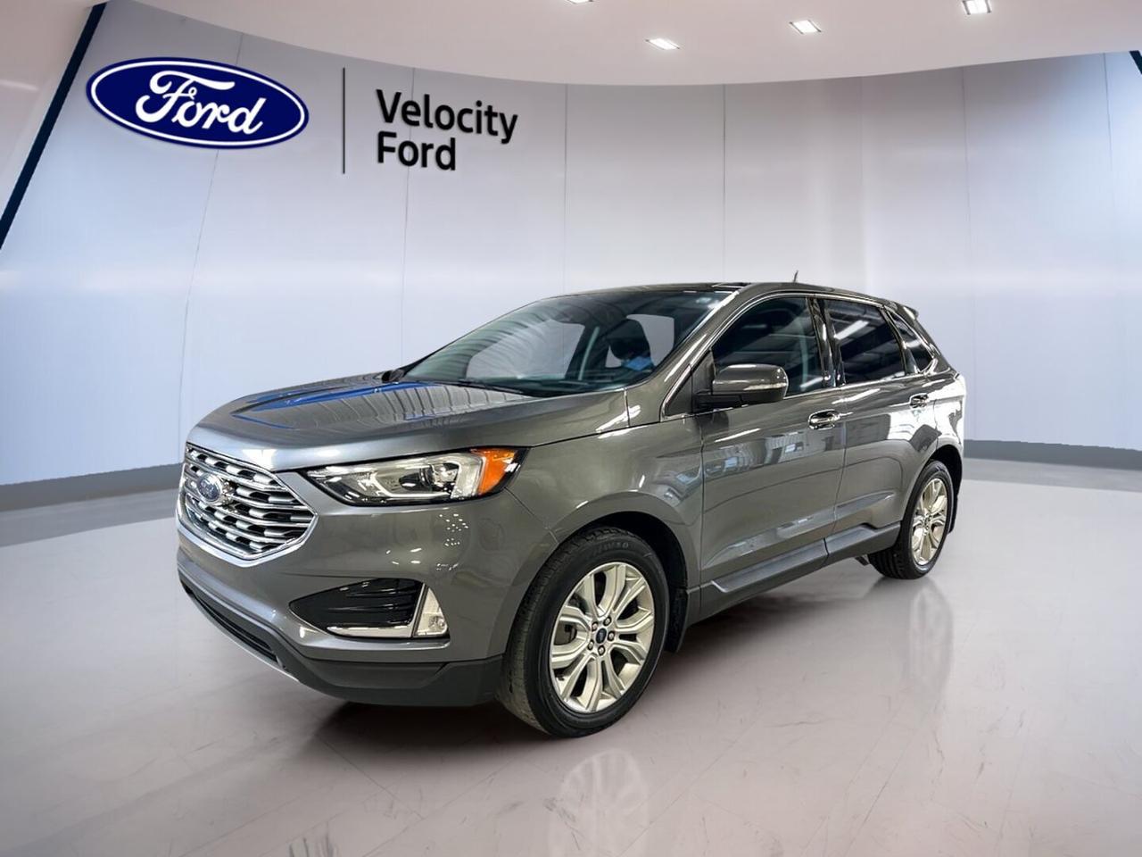 Finished in Grey with a Black interior, this used 2021 Ford Edge Titanium AWD delivers a refined midsize SUV experience with confident all-weather capability. Sold by Velocity Ford in Moose Jaw, it pairs a 2.0-litre unleaded engine with an 8-speed automatic transmission and has 140,939 km on the odometer.

The 2021 Ford Edge Titanium AWD is built for drivers who want comfort, smart safety, and everyday versatility. Four doors, a roomy cabin, and a practical liftgate make it easy to handle family duty, commuting, and weekend travel. Its upscale look is matched by useful features that add real value every day.

FEATURES OF THE Edge Titanium AWD
»» Grey exterior with sleek modern presence
»» All-wheel drive for added traction
»» Power liftgate for easier loading
»» Heated front seats for cold mornings

ADVANCED SAFETY FEATURES
»» Backup camera helps with tight parking
»» Blind spot monitor boosts lane awareness
»» Lane departure warning adds extra confidence
»» Side and head airbags enhance protection

PERFORMANCE AND EFFICIENCY
»» 2.0-litre unleaded engine balances power efficiently
»» 8-speed automatic supports smooth shifting
»» All-wheel drive improves year-round traction
»» Limited slip differential aids grip

COMFORT AND CONVENIENCE
»» Dual-zone climate control keeps comfort balanced
»» Remote starter adds convenience in winter
»» Memory settings simplify shared driving
»» Power windows and locks add ease

TECHNONOLGY AND CONNECTIVITY
»» Bluetooth integration supports hands-free communication
»» WiFi hotspot helps keep devices connected
»» Satellite radio expands entertainment choices
»» Steering wheel audio controls feel intuitive

CARGO SPACE
»» Power liftgate improves cargo access
»» Rear trunk access is simple
»» Four-door design supports daily practicality
»» Spacious layout suits errands and trips

AWARDS & RECOGNITIONS
»» Top Safety Pick, Insurance Institute for Highway Safety, 2021

WHAT OTHER OWNERS LIKE
»» Quiet highway ride and solid comfort
»» User-friendly infotainment and easy controls
»» Confident all-wheel drive in winter
»» Spacious cabin for passengers and gear

This 2021 Ford Edge Titanium AWD also includes many sought-after features that support a premium driving experience. Cruise control and power steering help make longer trips easier. Anti-Lock Braking System, stability control, child safety locks, and tire pressure monitoring add reassurance for daily driving in changing road conditions.

Inside, the 2021 Ford Edge Titanium AWD offers thoughtful details that drivers notice right away. Heated mirrors, power mirrors, tinted windows, automatic headlights, fog lights, ambient lighting, push-button start, and an auto-dimming rearview mirror all contribute to a polished and convenient cabin environment.

Comfort remains a key strength in this 2021 Ford Edge Titanium AWD. Front air conditioning, automatic climate control, drivers seat lumbar support, passenger lumbar support, power front seats, and an adjustable steering wheel help create a relaxed drive. Illuminated vanity mirrors and rear window defroster add useful touches for everyday ownership.

This SUV also brings strong technology value. HD Radio, Bluetooth integration, a backup camera, and steering wheel audio controls keep key functions close at hand. Turn signal mirrors, LED headlamps, and memory mirrors round out a well-equipped package designed for real Canadian driving needs.

This 2021 Ford Edge Titanium AWDs VIN is: 2FMPK4K92MBA29205.