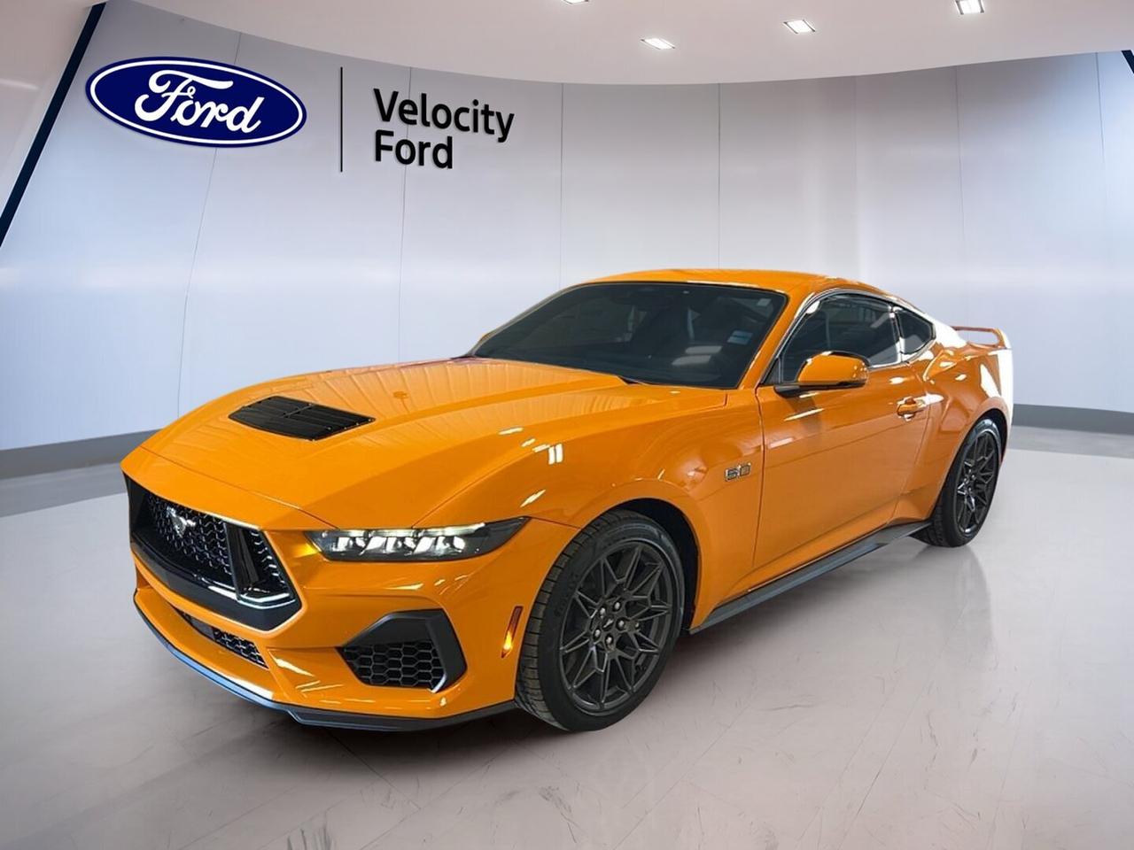 Brand new and built to excite, this 2026 Ford Mustang GT Premium Fastback brings classic V8 performance to Moose Jaw with a bold Orange exterior, Black interior, and a driver-focused 6-speed manual transmission. With 2 doors, a 5.0-litre unleaded engine, and premium comfort features, this Ford delivers a pure sports car experience with modern daily usability.

The 2026 Ford Mustang GT Premium Fastback blends track-inspired character with smart convenience for every drive. From the limited slip differential and rear spoiler to heated front seats and dual-zone climate control, this coupe feels ready for open highways, weekend cruises, and the kind of driving that rewards every shift.

FEATURES OF THE Mustang GT Premium Fastback
»» 5.0-litre V8 power with manual control
»» Rear spoiler adds sporty visual appeal
»» Limited slip differential boosts traction
»» Premium cabin with heated front seats

ADVANCED SAFETY FEATURES
»» Backup camera helps with tight parking
»» Lane departure warning adds driving support
»» Blind spot monitor improves lane awareness
»» Multiple airbags enhance occupant protection

PERFORMANCE AND EFFICIENCY
»» 5.0-litre unleaded engine delivers strong response
»» 6-speed manual transmission boosts driver engagement
»» Limited slip differential aids corner exit
»» Performance tires support confident road grip

COMFORT AND CONVENIENCE
»» Heated front seats help cold mornings
»» Dual-zone climate control adds comfort
»» Power driver seat with lumbar support
»» Push button start adds daily ease

TECHNOLOGY AND CONNECTIVITY
»» Bluetooth integration supports hands-free communication
»» WiFi hotspot keeps devices connected
»» Satellite radio expands entertainment choices
»» Steering wheel audio controls simplify use

CARGO SPACE
»» Rear trunk access supports easy loading
»» Useful trunk space for weekend bags
»» Coupe design still offers practical storage
»» Cabin storage helps organize small items

WHAT OTHER OWNERS LIKE
»» Strong V8 sound and manual shifting
»» Comfortable ride with premium daily features
»» Confident handling with balanced road feel
»» Easy-to-use technology and clear controls

This Ford coupe is well equipped with cruise control, power steering, anti-lock braking system, stability control, automatic headlights, LED headlamps, electric mirrors, power windows, rear window defroster, automatic door locks, and tire pressure monitoring. These features help make each drive simple, secure, and enjoyable in changing Prairie conditions.

Inside, the cabin is designed around the driver with automatic climate control, front air conditioning, ambient lighting package, an adjustable steering wheel, illuminated driver and passenger vanity mirrors, an auto-dimming rearview mirror, and an electric passenger seat. The layout is clean and functional, giving this 2026 Ford Mustang GT Premium Fastback a refined feel without losing its performance focus.

Entertainment and convenience are also strong points. HD Radio, satellite radio, Bluetooth integration, and steering wheel audio controls keep key functions close at hand. Rear trunk access adds everyday practicality, while the backup camera helps when reversing in busy lots or narrow spaces around town.

For drivers who want real V8 character, a manual gearbox, and modern features in one exciting package, this brand new 2026 Ford Mustang GT Premium Fastback stands out at Velocity Ford in Moose Jaw. It offers authentic performance, premium comfort, and the timeless appeal of a true Ford sports coupe.

This 2026 Ford Mustang GT Premium Fastbacks VIN is: 1FA6P8CFXT5406742.
