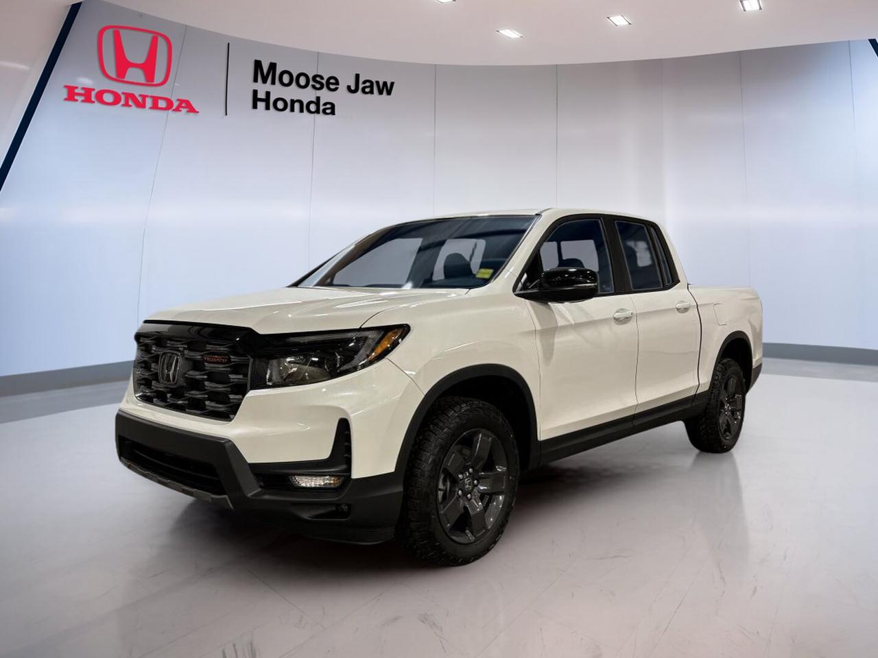 Built for Canadian roads and ready for work or play, the brand new 2026 Honda Ridgeline Trailsport brings proven V6 power, confident all-wheel drive, and smart truck utility to Moose Jaw Honda. Finished in White with a Black interior, this midsize pickup blends comfort, capability, and everyday ease in one well-rounded package.

The 2026 Honda Ridgeline Trailsport stands out with a durable unibody design, a smooth 9-Speed Automatic transmission, and Honda intelligent all-wheel drive. It is made for drivers who want a truck that feels refined in town, stable on the highway, and capable when the pavement ends.

FEATURES OF THE Ridgeline Trailsport
»» Trail-ready suspension tuning for rough roads
»» Standard all-wheel drive for added confidence
»» V6 power for strong daily performance
»» Durable design with practical truck versatility

ADVANCED SAFETY FEATURES
»» Honda Sensing suite supports safer driving
»» Collision mitigation braking can help react
»» Lane keeping assist supports highway confidence
»» Adaptive cruise control helps reduce fatigue

PERFORMANCE AND EFFICIENCY
»» 3.5-litre i-VTEC V6 delivers strong power
»» 9-speed automatic shifts smoothly and quickly
»» All-wheel drive boosts traction in Canada
»» Unibody truck design improves ride comfort

COMFORT AND CONVENIENCE
»» Spacious cabin offers everyday driving comfort
»» Black interior gives a clean look
»» Four-door layout helps passenger access easily
»» Smooth ride suits commuting and road trips

TECHNOLOGY AND CONNECTIVITY
»» Clear driver information supports easy monitoring
»» Modern controls are simple to use
»» Automatic transmission includes manual shift control
»» Useful cabin tech supports daily driving

TRUCK FEATURES
»» Strong V6 supports confident towing capability
»» Pickup bed adds everyday hauling flexibility
»» All-wheel drive helps on loose surfaces
»» Rugged setup suits work and weekend use

CARGO SPACE
»» Truck bed handles gear and supplies
»» Cabin storage helps organize smaller items
»» Flexible layout supports passengers and cargo
»» Practical design suits active daily life

WHAT OTHER OWNERS LIKE
»» Smooth ride compared with traditional trucks
»» Useful bed and clever cargo solutions
»» Strong V6 power for daily driving
»» Comfortable cabin for long-distance travel

The 2026 Honda Ridgeline Trailsport is a smart choice for drivers who need real truck function without giving up comfort. Its White exterior looks clean and confident, while the Black interior keeps the cabin practical and easy to maintain through changing Prairie seasons.

At Moose Jaw Honda in Moose Jaw, this brand new 2026 Honda Ridgeline Trailsport is ready to help with commuting, family duty, road trips, and weekend projects. If you want a pickup with dependable Honda engineering, smooth power delivery, and versatile all-wheel-drive capability, this truck deserves a close look.

This 2026 Honda Ridgeline Trailsports VIN is: 5FPYK3F66TB501725.<p> and everyday ease in one well-rounded package.

The 2026 Honda Ridgeline Trailsport stands out with a durable unibody design</p>
<p> and Honda intelligent all-wheel drive. It is made for drivers who want a truck that feels refined in town</p>
<p> and capable when the pavement ends.

FEATURES OF THE Ridgeline Trailsport
»» Trail-ready suspension tuning for rough roads
»» Standard all-wheel drive for added confidence
»» V6 power for strong daily performance
»» Durable design with practical truck versatility

ADVANCED SAFETY FEATURES
»» Honda Sensing suite supports safer driving
»» Collision mitigation braking can help react
»» Lane keeping assist supports highway confidence
»» Adaptive cruise control helps reduce fatigue

PERFORMANCE AND EFFICIENCY
»» 3.5-litre i-VTEC V6 delivers strong power
»» 9-speed automatic shifts smoothly and quickly
»» All-wheel drive boosts traction in Canada
»» Unibody truck design improves ride comfort

COMFORT AND CONVENIENCE
»» Spacious cabin offers everyday driving comfort
»» Black interior gives a clean look
»» Four-door layout helps passenger access easily
»» Smooth ride suits commuting and road trips

TECHNOLOGY AND CONNECTIVITY
»» Clear driver information supports easy monitoring
»» Modern controls are simple to use
»» Automatic transmission includes manual shift control
»» Useful cabin tech supports daily driving

TRUCK FEATURES
»» Strong V6 supports confident towing capability
»» Pickup bed adds everyday hauling flexibility
»» All-wheel drive helps on loose surfaces
»» Rugged setup suits work and weekend use

CARGO SPACE
»» Truck bed handles gear and supplies
»» Cabin storage helps organize smaller items
»» Flexible layout supports passengers and cargo
»» Practical design suits active daily life

WHAT OTHER OWNERS LIKE
»» Smooth ride compared with traditional trucks
»» Useful bed and clever cargo solutions
»» Strong V6 power for daily driving
»» Comfortable cabin for long-distance travel

The 2026 Honda Ridgeline Trailsport is a smart choice for drivers who need real truck function without giving up comfort. Its White exterior looks clean and confident</p>
<p> while the Black interior keeps the cabin practical and easy to maintain through changing Prairie seasons.

At Moose Jaw Honda in Moose Jaw</p>
<p> this truck deserves a close look.

This 2026 Honda Ridgeline Trailsports VIN is: 5FPYK3F66TB501725.</p>
