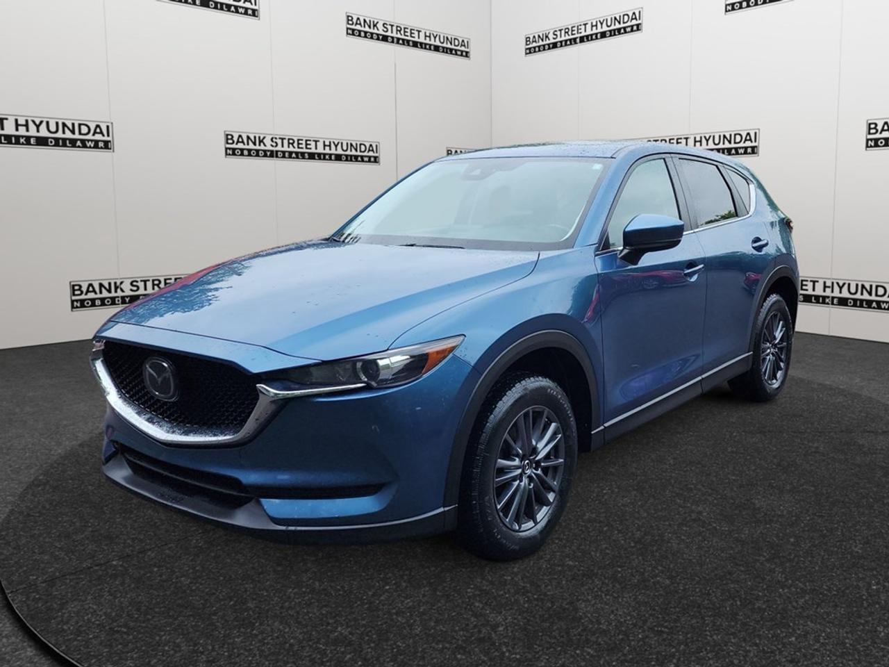 Introducing the 2019 Mazda CX-5 GS Auto AWD in a stunning blue finish, offering a smooth and confident drive with its all-wheel drive capabilities and adept handling. The exterior captures attention with its refined yet assertive SUV presence, complemented by stylish alloy wheels and practicality enhancing heated mirrors. Inside, the CX-5 exudes comfort and elegance, featuring heated front seats, a leather steering wheel, and leatherette door trim inserts. The convenience of keyless entry and the functionality of power seats ensure a driver-focused experience. Technology enthusiasts will appreciate the smart device integration for seamless connectivity, while the Bluetooth connection allows for hands-free communication. Safety remains a priority with an array of advanced features including a backup camera, lane assist, and adaptive cruise control, all designed to offer peace of mind on the road. This vehicle is perfect for families and individuals who prioritize comfort, safety, and technology in their daily drives. Contact Bank Street Hyundai today to learn more about how the 2019 Mazda CX-5 GS Auto AWD can elevate your journey.