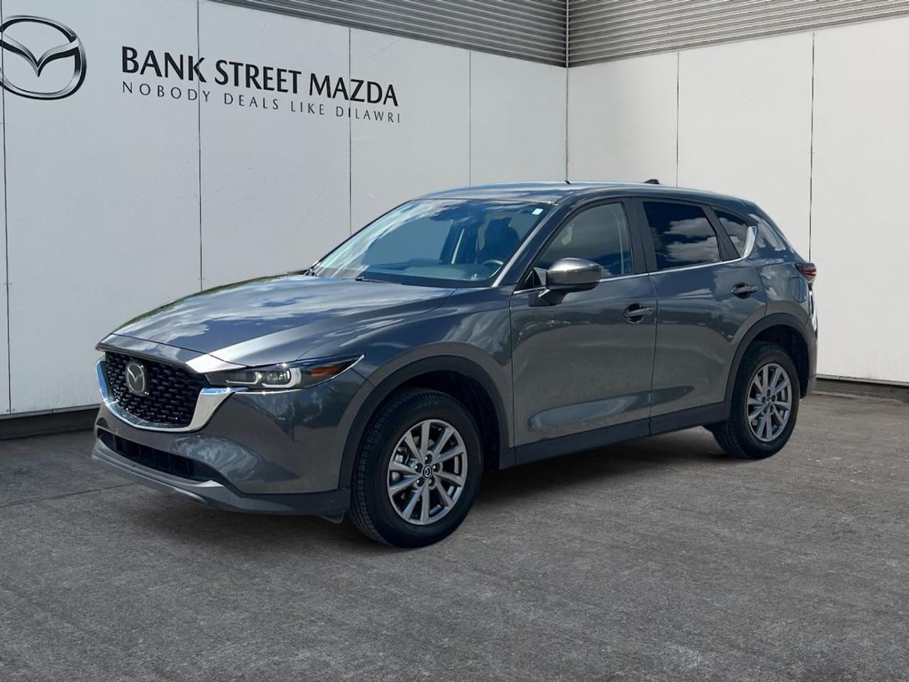 Experience the refined 2024 Mazda CX-5 GS in a stylish gray finish, equipped with AWD for unbeatable handling. This SUV is a blend of elegance and functionality, offering a comprehensive driving experience. The exterior is accentuated with alloy wheels and heated mirrors, combining durability with a touch of sophistication. Inside, enjoy the comfort of heated front seats and a leather steering wheel that complements the leather gear shifter material and leatherette door trim, creating an inviting atmosphere for both driver and passengers. Equipped with modern technology, the CX-5 features smart device integration, a backup camera, and Bluetooth connectivity, making every drive seamless and connected. Safety is paramount with adaptive cruise control, lane assist, and brake assist enhancing your driving confidence. If youre looking for a versatile and stylish SUV that fits the lifestyle of active individuals and families alike, the 2024 Mazda CX-5 GS is perfect for you. Visit Bank Street Mazda for a test drive and see why this vehicle should be your next purchase.