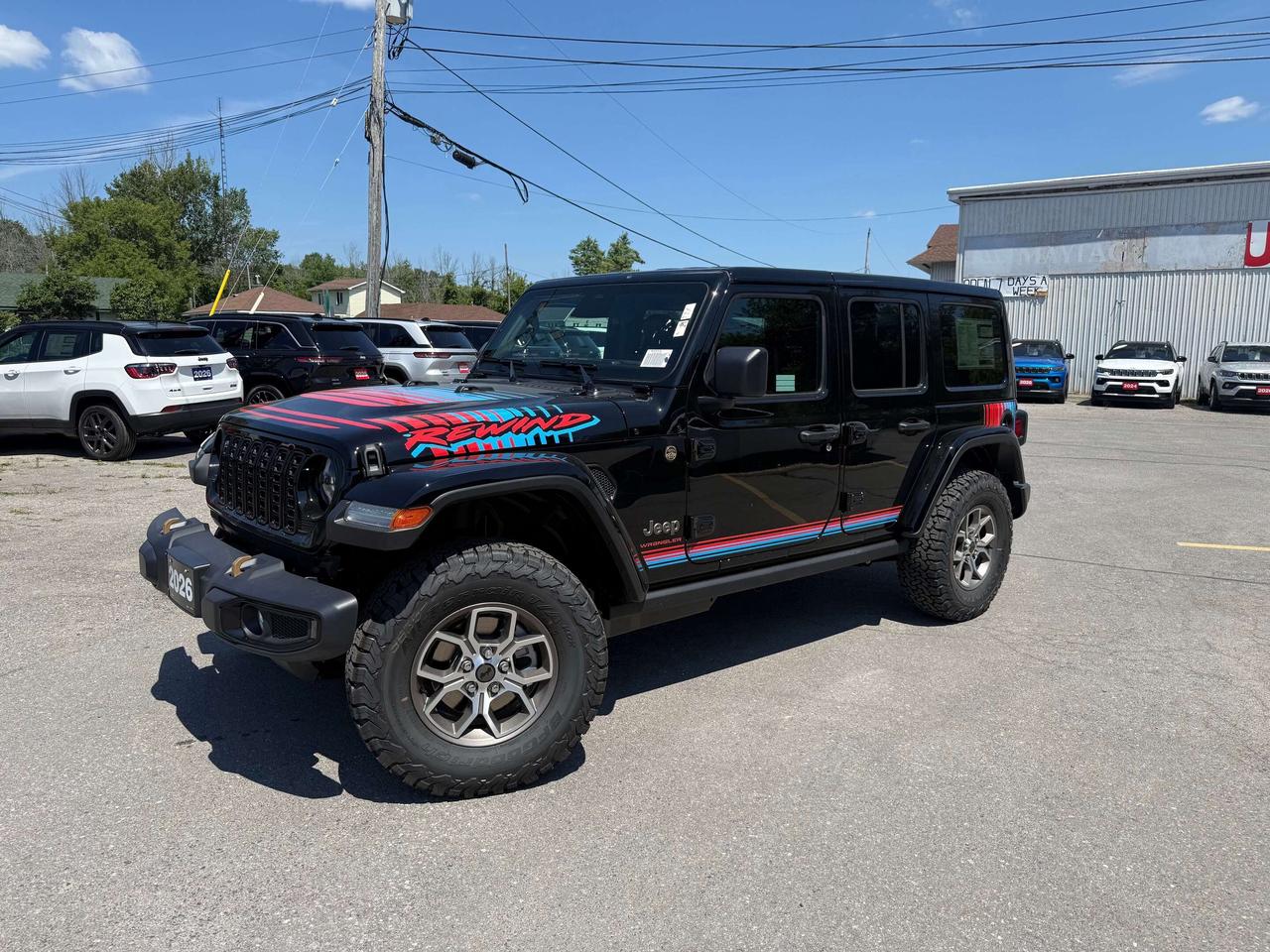 2026 JEEP WRANGLER REWIND 4 DOOR 4X4.  3.6L PENTASTAR ENGINE WITH 8 SPEED AUTO TRANSMISSION.  12.3" SCREEN WITH APPLE CARPLAY OR ANDROID AUTO, DUAL TOP GROUP, ALPINE SOUND SYSTEM, RETRO LEATHER SEATS WITH BLUE & PURPLE STITCHING, POWER DRIVER & PASSENGER SEATS, 4.10 REAR AXLE RATIO, CORNING GORILLA GLASS, HEATED SEATS & STEERING WHEEL, REMOTE START, REWIND SPARE TIRE COVER, ADAPTIVE CRUISE CONTROL, FORWARD COLLISION WARNING PLUS, DANA M210 WIDE HEAVY-DUTY TUBE FRONT AXLE, DANA M220 WIDE REAR AXLE, UNIVERSAL GARAGE DOOR OPENER, & MORE!  ONLY HST EXTRA.