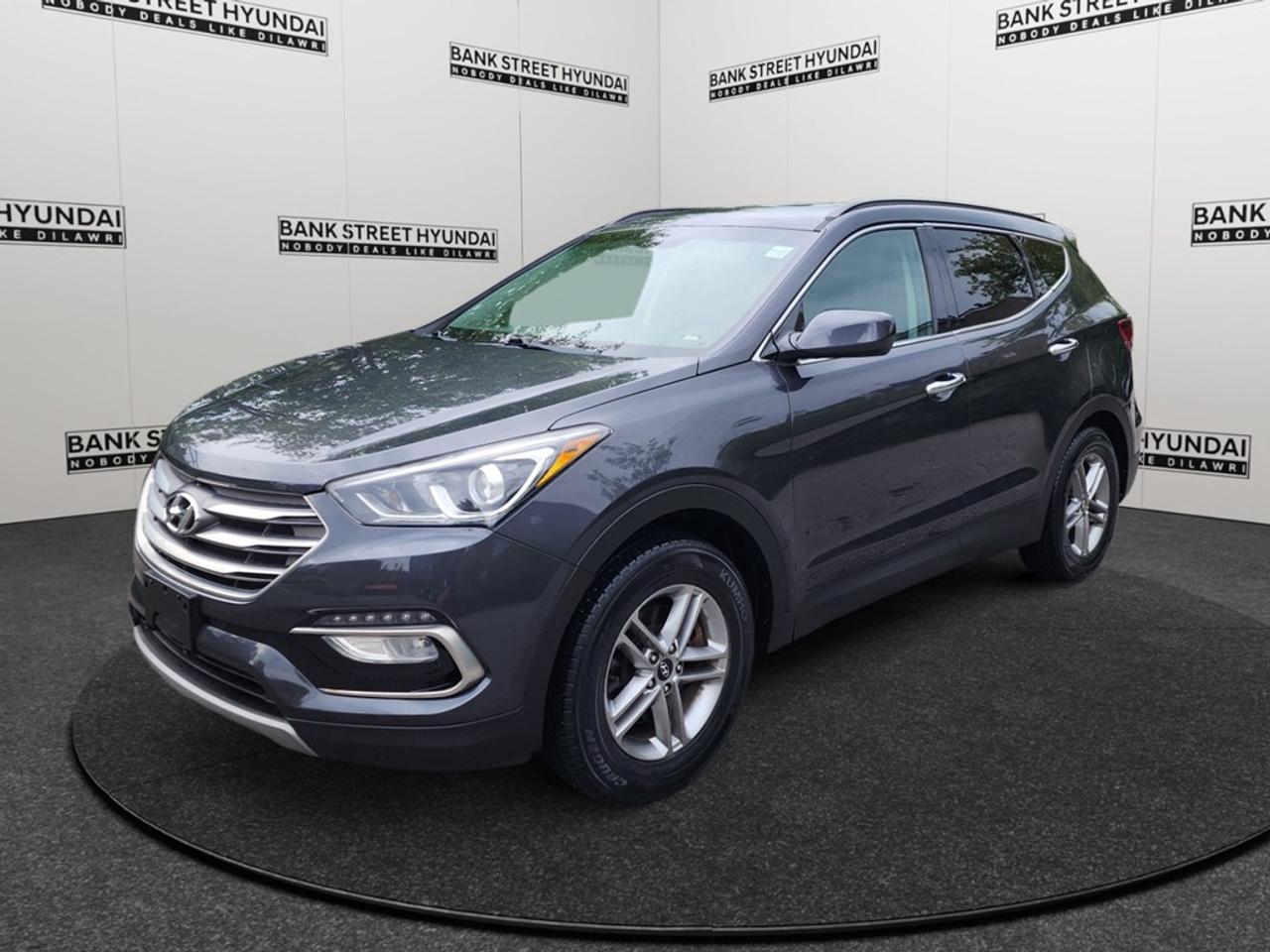 Explore the refined 2018 Hyundai Santa Fe Sport, finished in a sophisticated gray, with a robust all-wheel drivetrain and smooth automatic transmission. Perfect for navigating any terrain with sure-footed handling, this SUV is ready for your next adventure. The sleek exterior is complemented by stylish alloy wheels and features like heated mirrors, while the interior invites you to experience comfort with heated front seats. Enjoy the convenience of keyless entry and power windows, along with the utility of air conditioning to maintain your ideal cabin environment. Stay connected effortlessly with the innovative Bluetooth connection, and drive with confidence using the backup camera for easy parking and maneuvering. Safety comes standard with brake assist, while cruise control ensures a relaxed journey. Experience the comfort of heated seats, making every drive a pleasure, no matter the season. Ideal for families and adventurers alike, the 2018 Hyundai Santa Fe Sport combines practicality with modern features. Contact Bank Street Hyundai today for more information and to arrange your test drive.