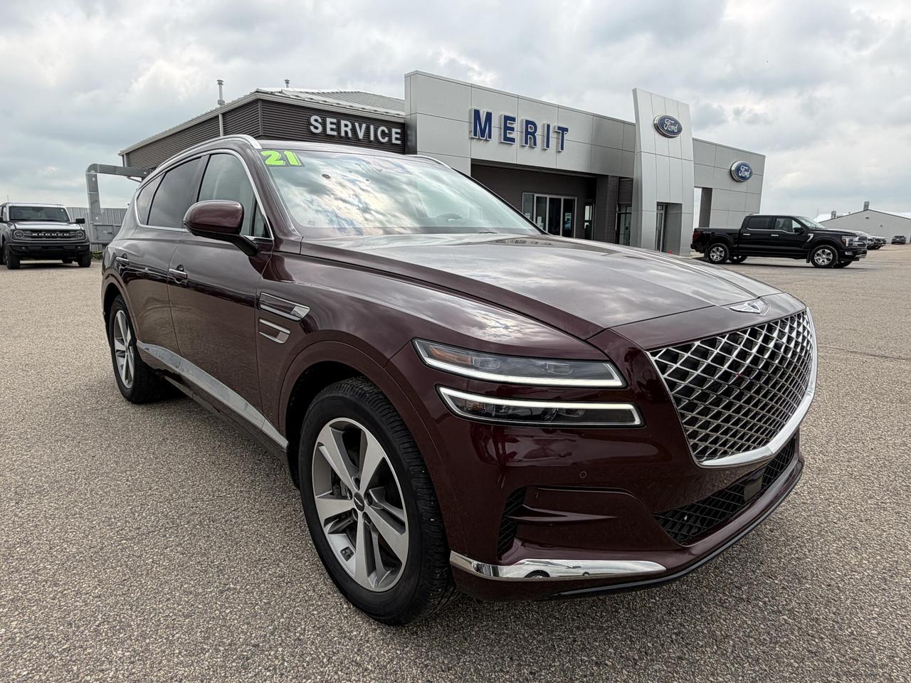 The 2021 Genesis GV80 2.5T Advanced in striking Lima Red delivers a level of sophistication and technology that punches well above its price point. With Highway Driving Assist II, a Head-Up Display, and a full suite of active safety systems, this AWD SUV is engineered for drivers who expect more from every kilometre.

- AWD with Electro-Mechanical Limited Slip Differential for confident, composed handling in all conditions
- Highway Driving Assist II (HDA II) with Smart Cruise Control w/Stop & Go for a capable semi-autonomous driving experience
- Head-Up Display keeps critical information in your sightline without distraction
- Aerial View Camera System and front/rear parking sensors make tight manoeuvres effortless
- 8-speed automatic with paddle shifters, rev-matching, and multiple drive modes (Comfort, Sport, Eco, Smart, Custom)
- 20 machine-finished aluminum alloy wheels on 265/50R20 all-season tires
- Heated leather steering wheel with auto tilt-away and power tilt/telescoping column
- Comprehensive safety suite including Driver Monitoring Alert, Evasion Assist, Blind Spot Collision Avoidance, and Collision Mitigation front and rear

At 98,000 km, this GV80 is well into its stride and ready for its next chapter. Visit Merit Ford Sales to book a test drive, or contact us with any questions  were happy to walk you through your purchase or financing options.