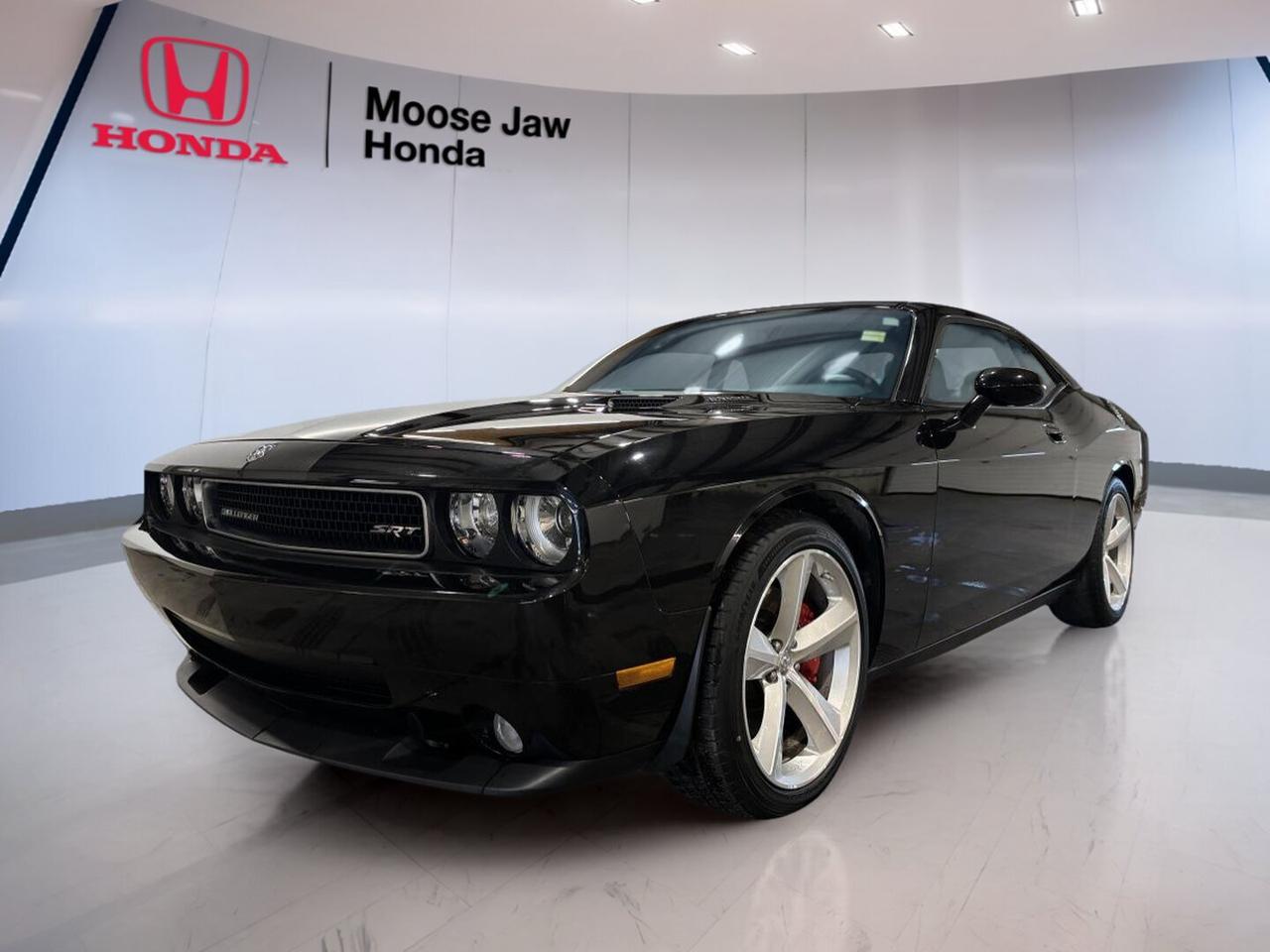 CARFAX Canada reports no accident.

Turn heads in this 2010 Dodge Challenger Srt8, now offered by Moose Jaw Honda in Moose Jaw. With just 13,254 km, a bold Black exterior, rear-wheel drive, and a 6.1L HEMI V8 engine, this coupe brings true muscle car character. The 2010 Dodge Challenger Srt8 blends classic Dodge style with modern power.

Built for drivers who want excitement, this 2010 Dodge Challenger Srt8 delivers strong V8 performance through a 5-speed automatic transmission. Its wide stance, confident road presence, and low kilometre reading make it a rare used performance coupe. This is a serious Dodge for collectors and enthusiasts alike.

FEATURES OF THE Challenger Srt8
»» 6.1L HEMI V8 delivers strong power
»» Five-speed automatic handles shifts with ease
»» Rear-wheel drive supports classic muscle feel
»» Low 13,254 km adds rare appeal

ADVANCED SAFETY FEATURES
»» Four-wheel disc brakes support controlled stopping
»» Electronic stability control helps maintain balance
»» Traction control aids grip on takeoff
»» Advanced front airbags enhance occupant protection

PERFORMANCE AND EFFICIENCY
»» HEMI V8 provides thrilling acceleration response
»» Rear-wheel drive delivers authentic coupe dynamics
»» Automatic transmission offers smooth power delivery
»» Performance-tuned chassis supports confident cornering

COMFORT AND CONVENIENCE
»» Two-door coupe design allows easy front access
»» Spacious cabin suits relaxed highway cruising
»» Air conditioning helps keep cabin comfortable
»» Cruise control supports easy long drives

TECHNOLOGY AND CONNECTIVITY
»» Clear driver gauges show vital information
»» Audio system supports daily entertainment needs
»» Steering wheel controls improve driver ease
»» Simple centre layout keeps functions accessible

CARGO SPACE
»» Trunk space handles weekend travel bags
»» Wide opening helps loading larger items
»» Rear seatback access adds carrying flexibility
»» Coupe design still offers useful storage

AWARDS & RECOGNITIONS
»» Best Resale Value Sports Car, Kelley Blue Book, 2010

WHAT OTHER OWNERS LIKE
»» Strong V8 sound and power delivery
»» Classic muscle styling with modern comfort
»» Stable highway ride and road presence
»» Low production feel and collector appeal

For drivers who appreciate real Dodge muscle, this coupe stands out with proven HEMI performance and very low kilometres. The Black finish adds a clean, aggressive look, while the automatic transmission makes this performance car easy to enjoy in town or on the open highway.

This used 2010 Dodge Challenger Srt8 is a smart choice for anyone seeking a memorable weekend car or a standout addition to a garage. It offers the sound, feel, and presence expected from a true Dodge performance coupe, backed by a clean CARFAX Canada report and available now at Moose Jaw Honda.

This 2010 Dodge Challenger Srt8s VIN is: 2B3CJ7DW0AH129422.