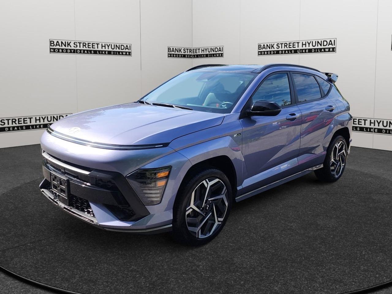 The 2024 Hyundai Kona N Line in stunning blue, equipped with an all-wheel-drive system, is designed to offer a dynamic and confident drive. This compact SUV effortlessly combines sporty handling with the practicality you need for everyday adventures. The Kona N Line features a cool yet bold exterior highlighted by its sleek lines and modern alloy wheels. Step inside to experience an interior that balances comfort and style, with heated leather seats and a leather steering wheel providing a touch of luxury. The N Line trim also includes a sunroof, enhancing the vehicles stylish aesthetics and allowing plenty of natural light in. The advanced technology built into this Kona ensures a connected and safe journey. Utilize the smart device integration and Bluetooth connection for seamless connectivity, while the integrated backup camera and lane assist are there to support you in every maneuver. Safety is further enhanced with features such as brake assist and adaptive cruise control, providing peace of mind on every drive. Perfect for urban explorers and families alike, the 2024 Hyundai Kona N Line appeals to those who value performance, technology, and style. Contact Bank Street Hyundai to learn more about this exceptional SUV and take it for a test drive today!